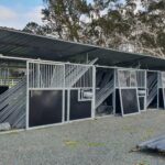 a lot of pipe front portable stables installed in a ranch.