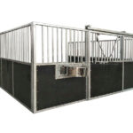 A metal horse stall featuring vertical bars and a sliding door, with dark panels on the lower part.