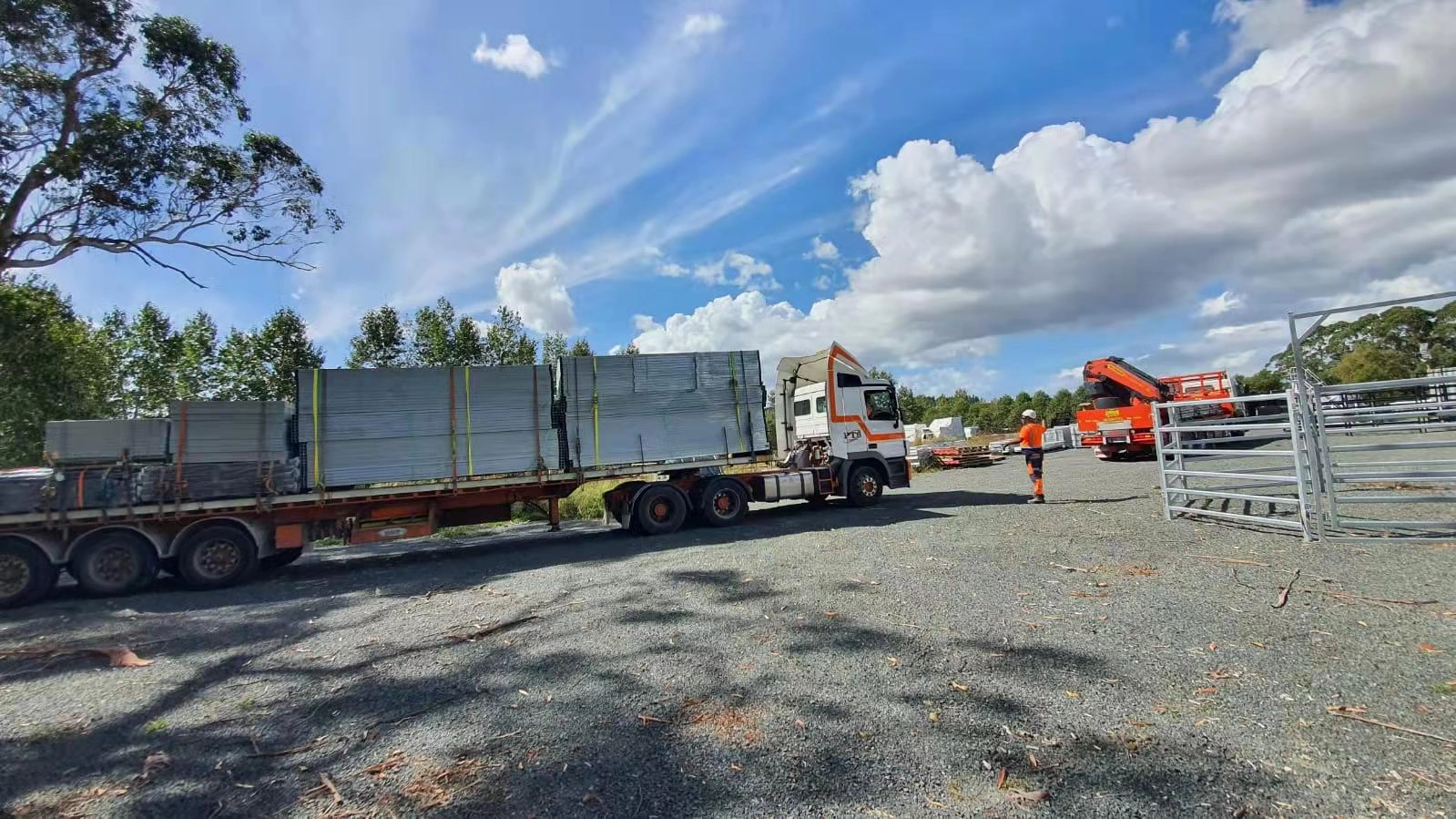 Large bundles of portable horse stable components are securely strapped on a flatbed truck for shipping to Australia. DB Stable expertly handles the logistics of exporting durable horse stables and flat pack kits to ensure safe delivery to the ANZ region.